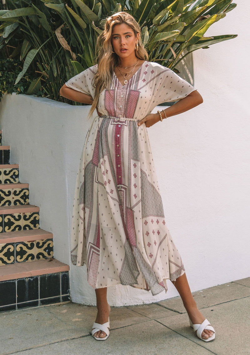 [Color: Natural/Wine] A model wearing a sheer chiffon maxi dress in a pink mixed print. With short dolman sleeves, a button front, an elastic waist, and a v neckline. 