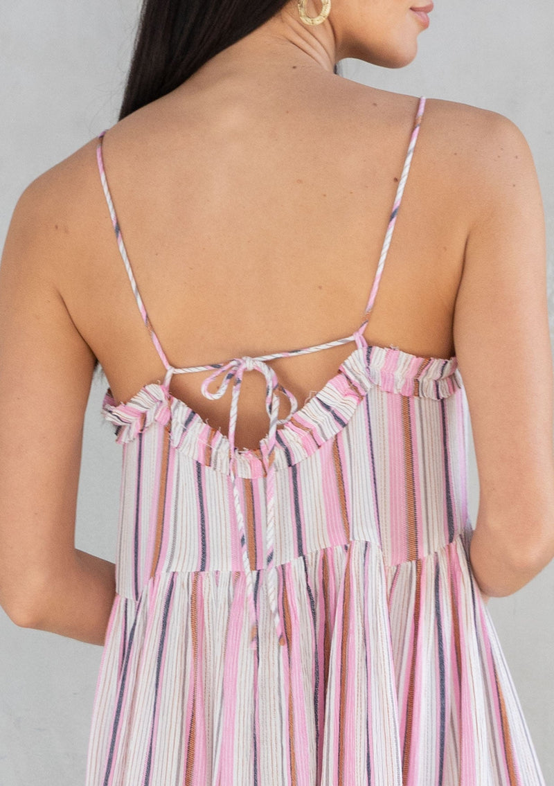 [Color: Natural/Pink] A model wearing a pink stripe sleeveless mini dress with a strappy back and flowy silhouette. 