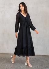 [Color: Black] A model wearing a gorgeous embroidered chiffon black maxi dress with an adjustable empire waist, tiered billowy skirt, long flattering sleeves, and lattice trim detail.