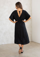 [Color: Black] A model wearing a black bohemian embroidered eyelet maxi dress with half length kimono sleeves, a surplice v neckline in front and back, and open back with tie detail, and a long flowy skirt. 