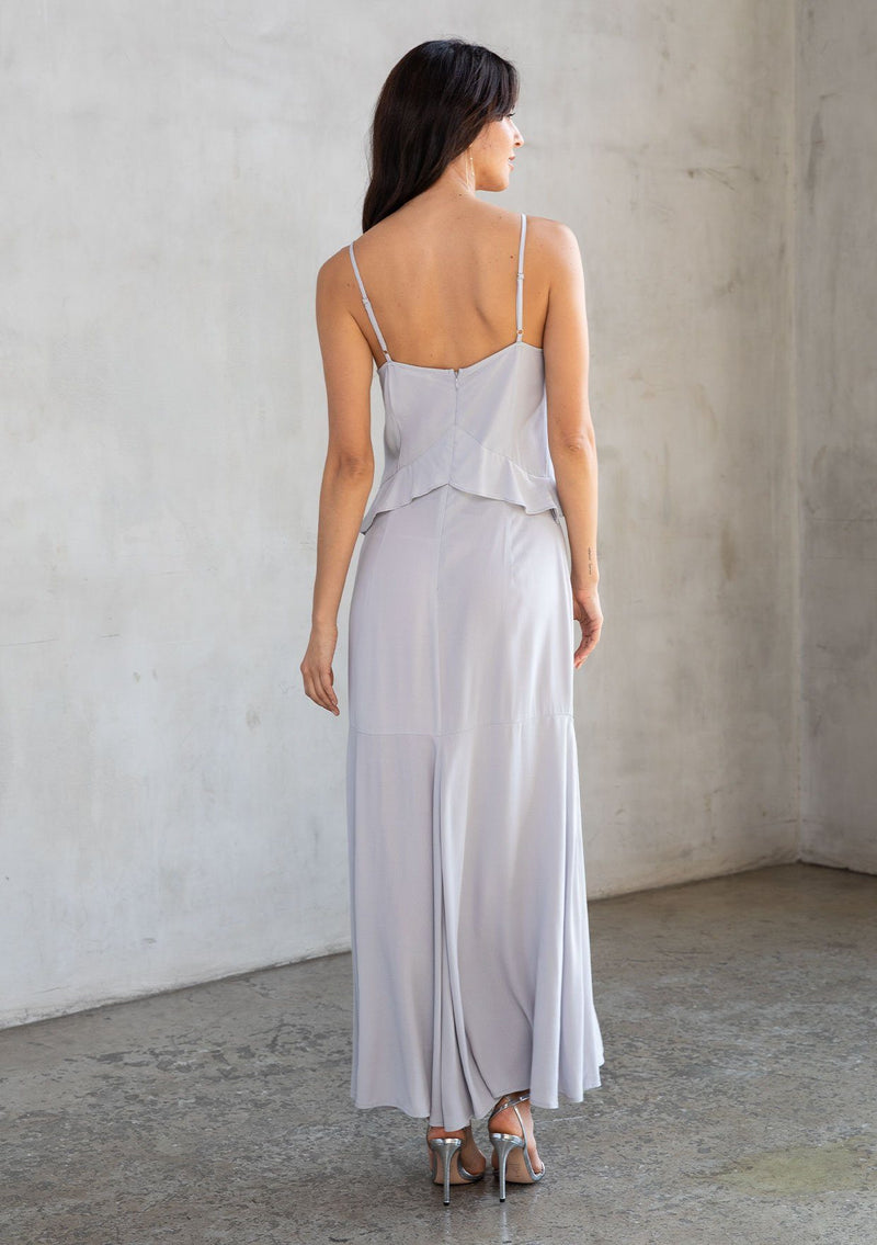 [Color: Platinum] A model wearing a stunning silver grey evening dress in textured crepe. With beaded trim, slim fit top and flowy skirt, ruffled neckline, and side slits. Perfect for holiday parties.