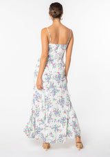 [Color: Ivory/Violet] A model wearing a white sleeveless maxi dress with purple floral print. With ruffled detail and spaghetti straps. 
