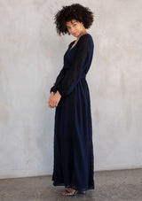 [Color: Navy/Black] A model wearing a dramatic sheer navy chiffon maxi dress with contrast black lace trim details throughout.