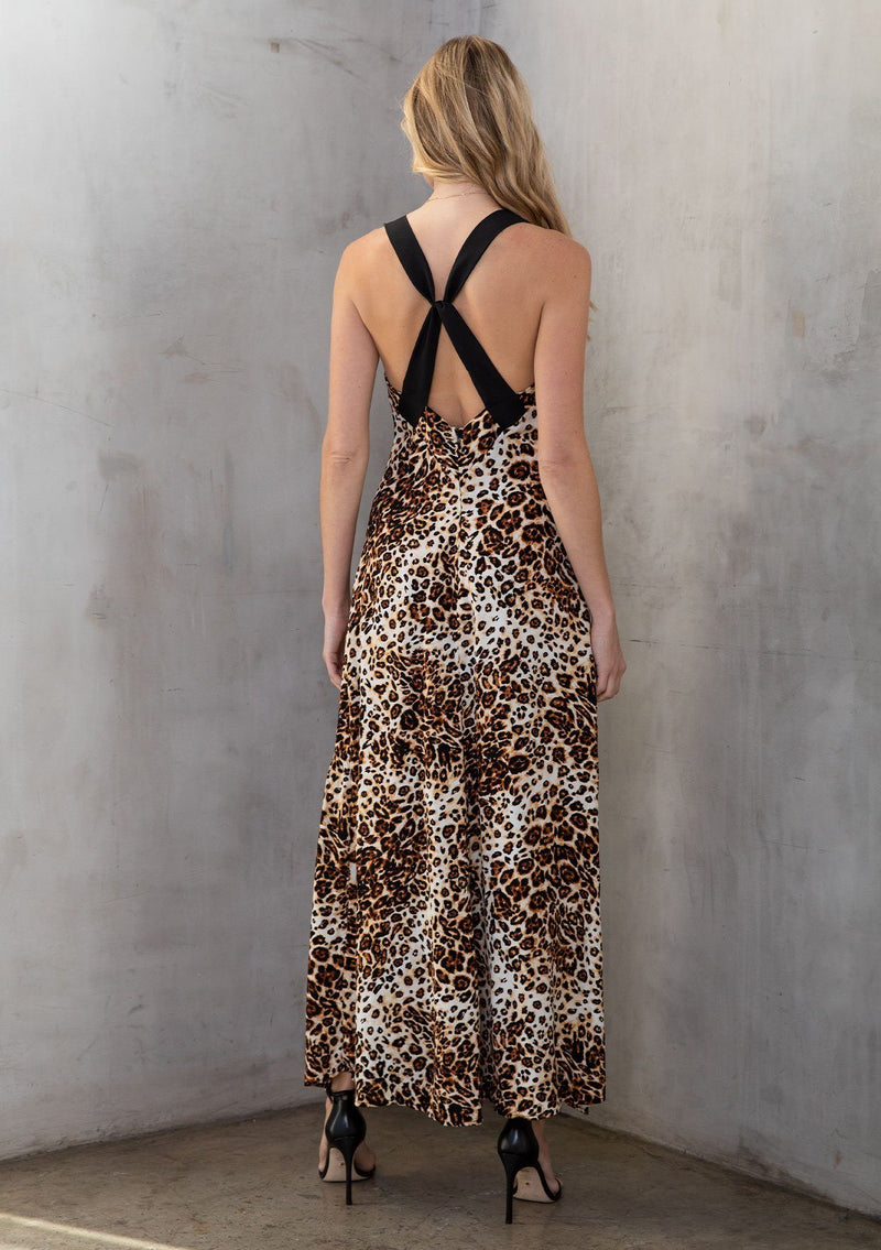 [Color: Camel/Brown] A model wearing a brown leopard print maxi dress with thick tank top straps, a deep v neckline, a cross back detail, side slits, and contrast trim. 