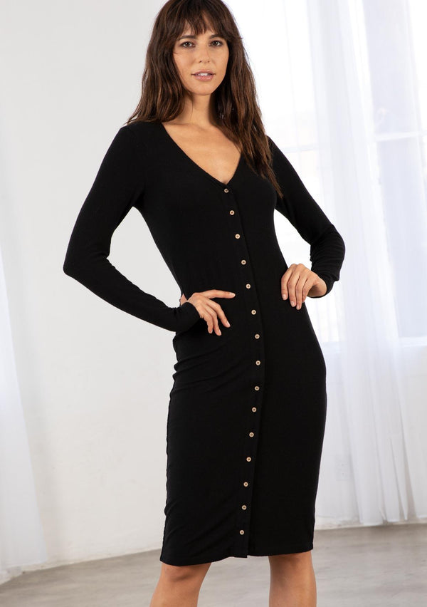 [Color: Black] A model wearing a slim fit black ribbed midi dress. Featuring long sleeves, a v neckline, and a button front. 
