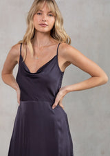 [Color: Gunmetal] A model wearing a sexy silky dark grey cowl neck maxi dress. With a half elastic waist at the back, a side slit, and an adjustable strappy back.