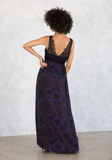 [Color: Black/Cobalt] A model wearing a black and blue paisley print bohemian maxi dress. With a lace overlay top, a v neckline, a side slit, and draped silhouette. 