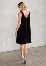 [Color: Black] A model wearing a black soft knit, holiday party mini dress with beaded straps, a deep v neckline in front and back, and a flowy swing silhouette. 
