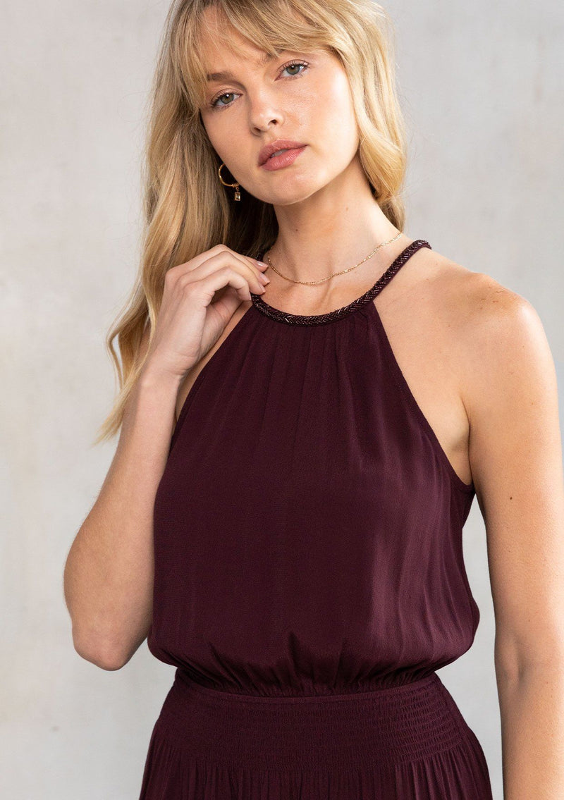 [Color: Fig] A model wearing a Holiday ready purple halter mini dress. A sexy dress for your next special occasion, with a beaded accent high neckline, a flattering open back with tassel tie closure, and a smocked elastic waist.