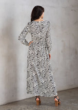[Color: Natural/Black] A model wearing a trendy maxi dress in a natural and black abstract circle print. With a square neckline, voluminously long sleeves, and a leg baring side slit.