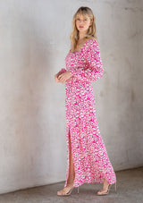 [Color: Natural/Fuchsia] A model wearing a trendy maxi dress in a natural and fuchsia pink abstract circle print. With a square neckline, voluminously long sleeves, and a leg baring side slit. 