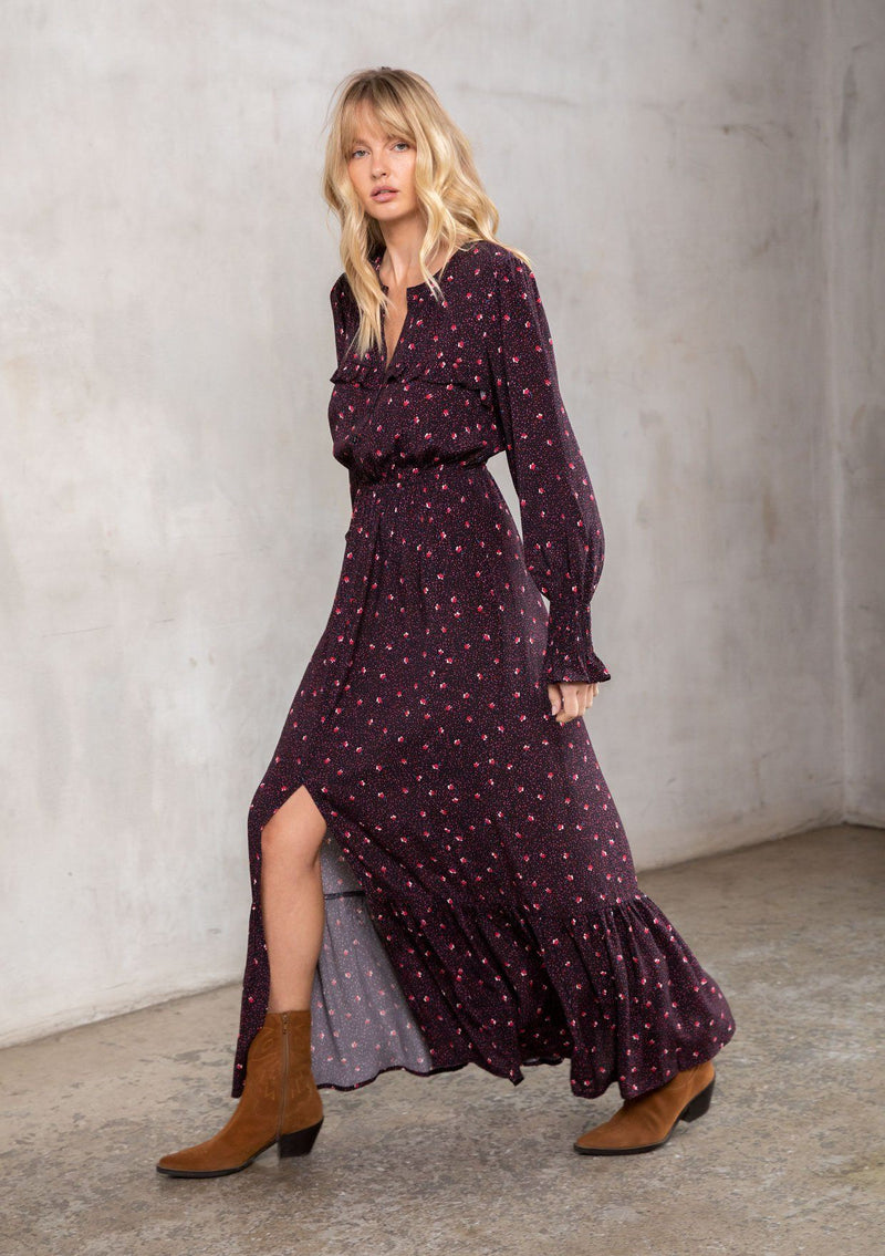 [Color: Black/Red] A model wearing a timeless bohemian black and red dot floral maxi dress. With long sleeves, a button front, and ruffled yoke detail. 