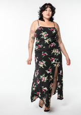 [Color: Black/Red] A model wearing a classic black bohemian maxi slip dress in a pink floral print. With adjustable spaghetti straps, a side slit, and lattice trim.