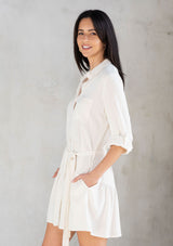 [Color: Vanilla] A model wearing a pretty off white linen blend mini shirtdress. With a flowy tiered skirt, a button front, and long rolled sleeves. 