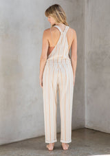 [Color: Natural/Terracotta] A model wearing a classic linen and cotton blend overalls in a terracotta yarn dye stripe. With adjustable straps and a long cuffed leg.