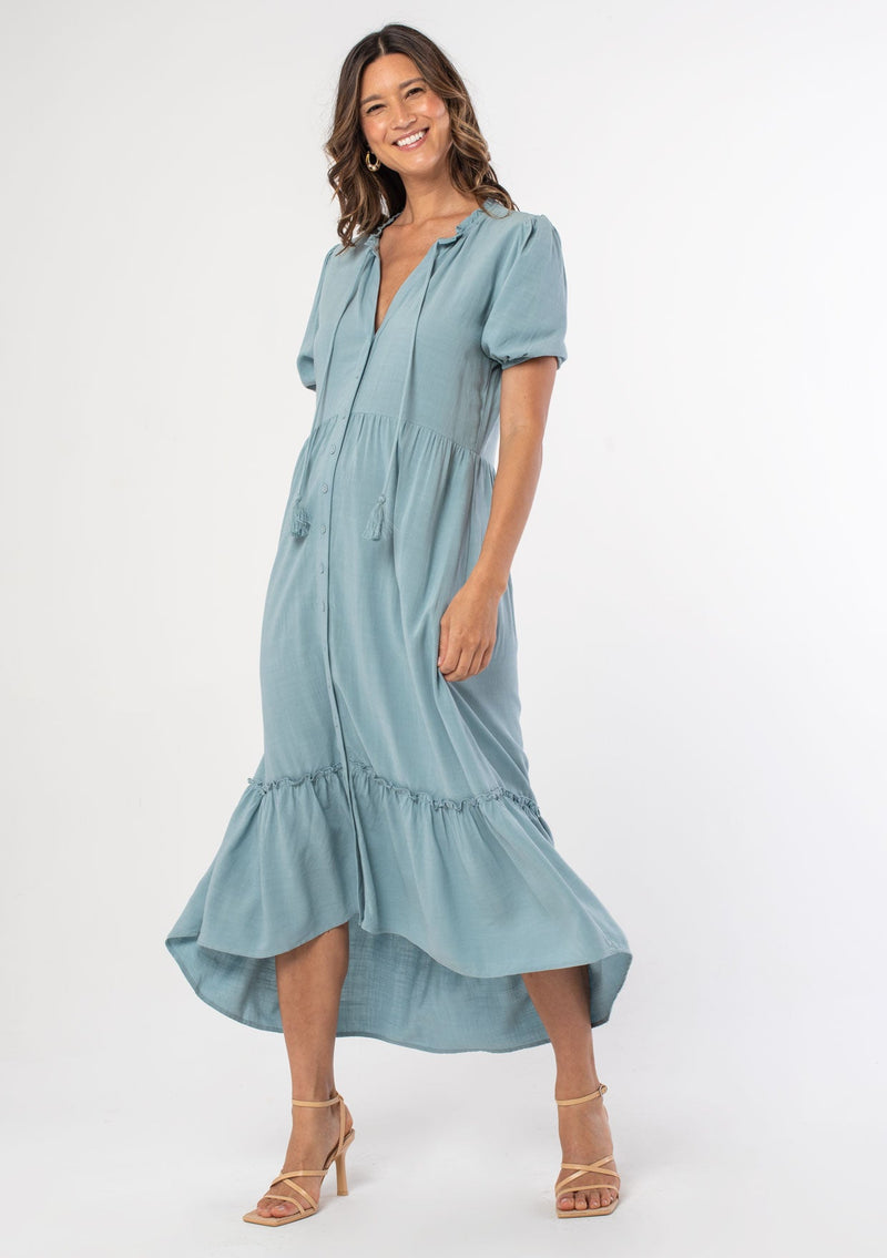 [Color: Dusty Teal] A model wearing a teal flowy bohemian mid length dress with a button front and short puff sleeves.