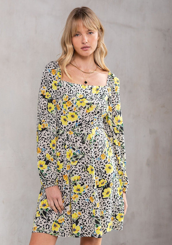 [Color: Ivory/Lemon] A model wearing a charming square neck mini dress in a yellow floral print. With bohemian voluminous long sleeves, a half smocked elastic bodice, and a flowy skirt. 