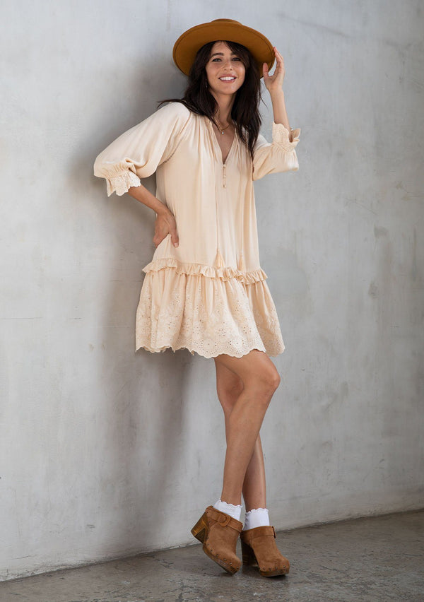 [Color: Natural] A model wearing a classic natural bohemian mini dress with a ruffle trimmed tiered skirt, button front, and embroidered detail throughout. 