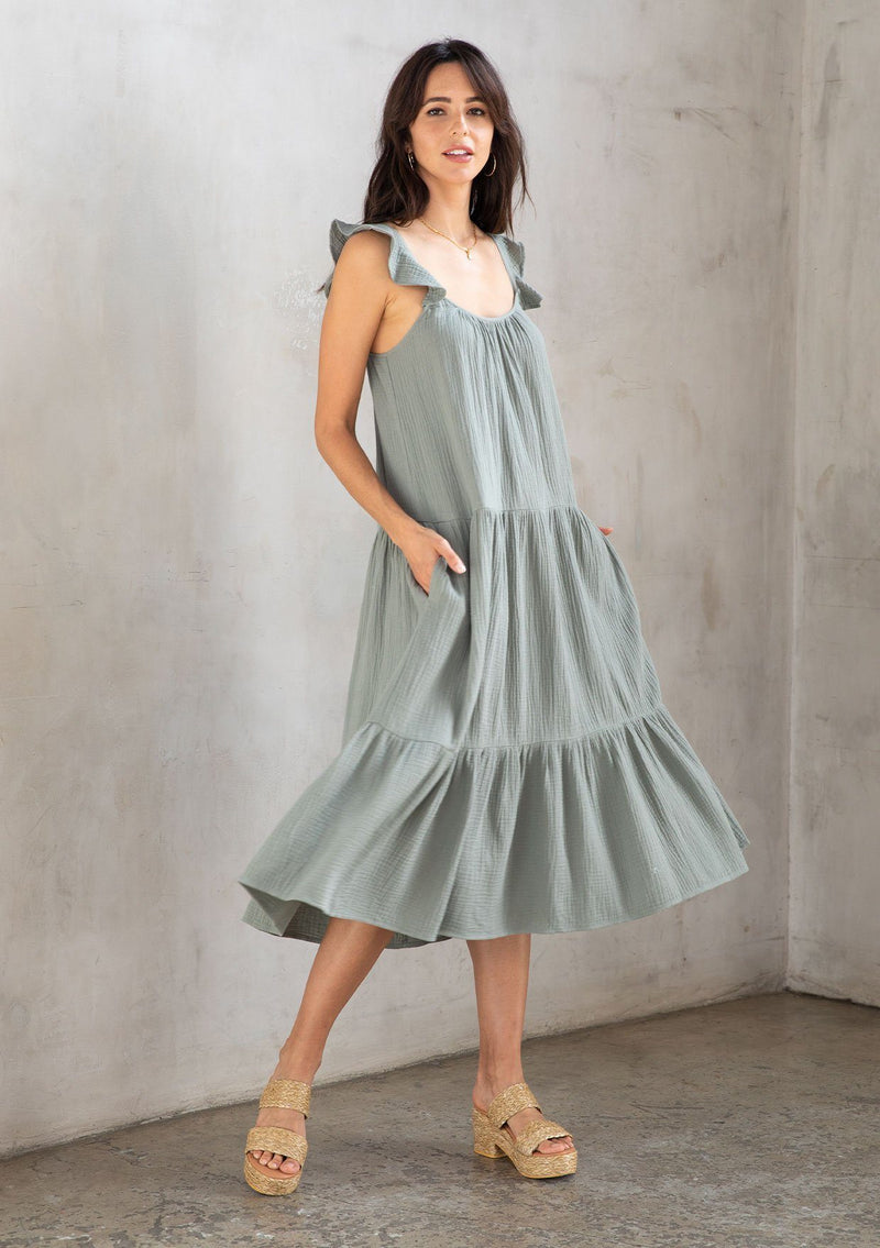 [Color: Silver Sage] A model wearing a cute sage green maxi dress designed in soft cotton gauze. With a scooped neckline, adjustable ruffled straps, and real side pockets.
