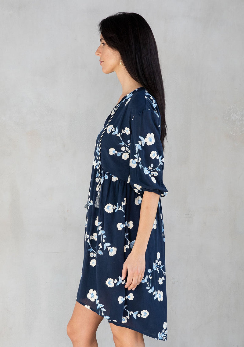 [Color: Navy/Ivory] A model wearing a flowy navy blue bohemian mini dress with floral embroidery. 