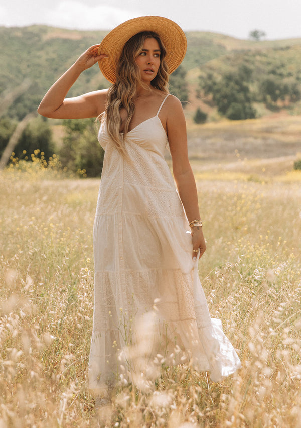 [Color: Natural] A woman wearing an off white bohemian cotton tank maxi dress with patchwork embroidery and dobby. With spaghetti straps and a button front.