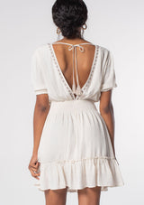 [Color: Off White/Taupe] A model wearing an off white linen blend spring mini dress with bohemian embroidered front, an open back, and flowy skirt. 