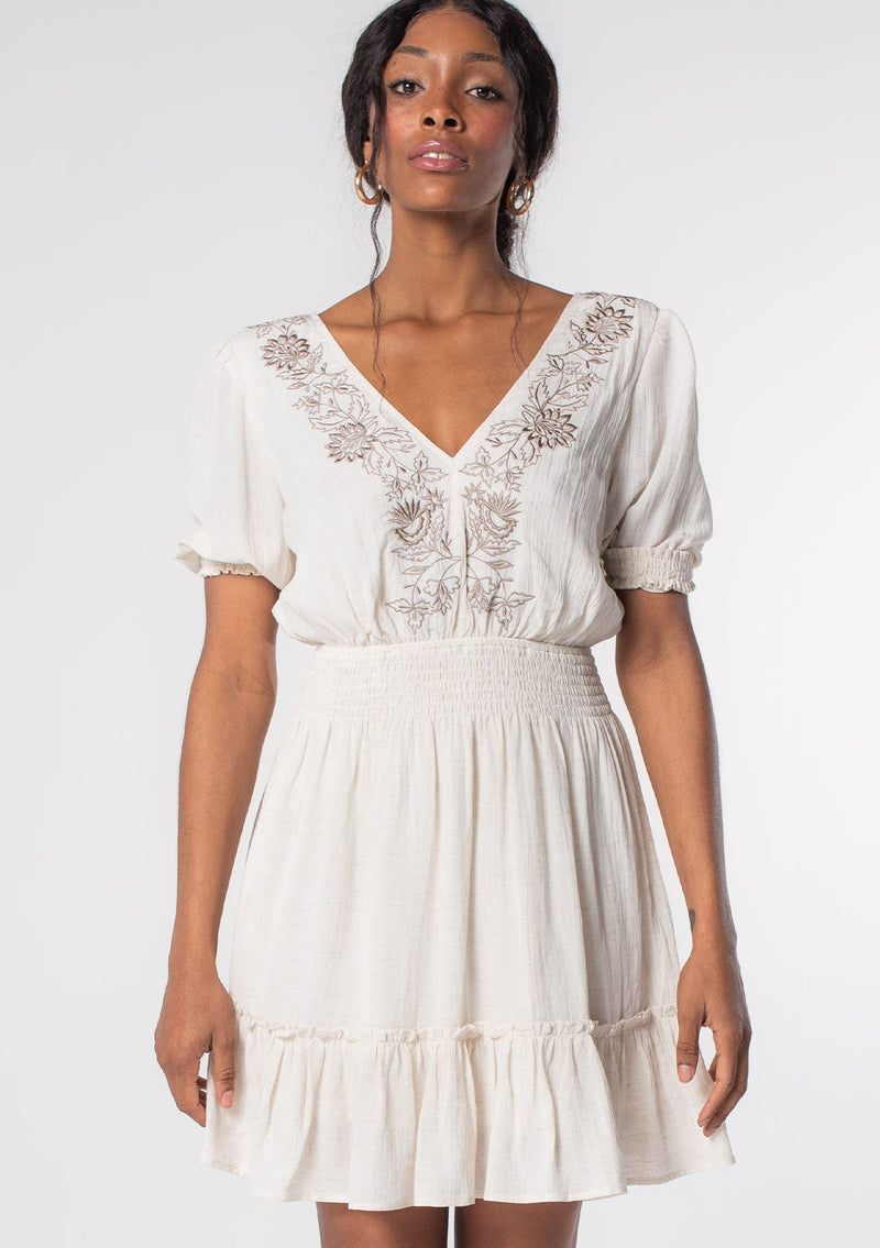 [Color: Off White/Taupe] A model wearing an off white linen blend spring mini dress with bohemian embroidered front, an open back, and flowy skirt. 