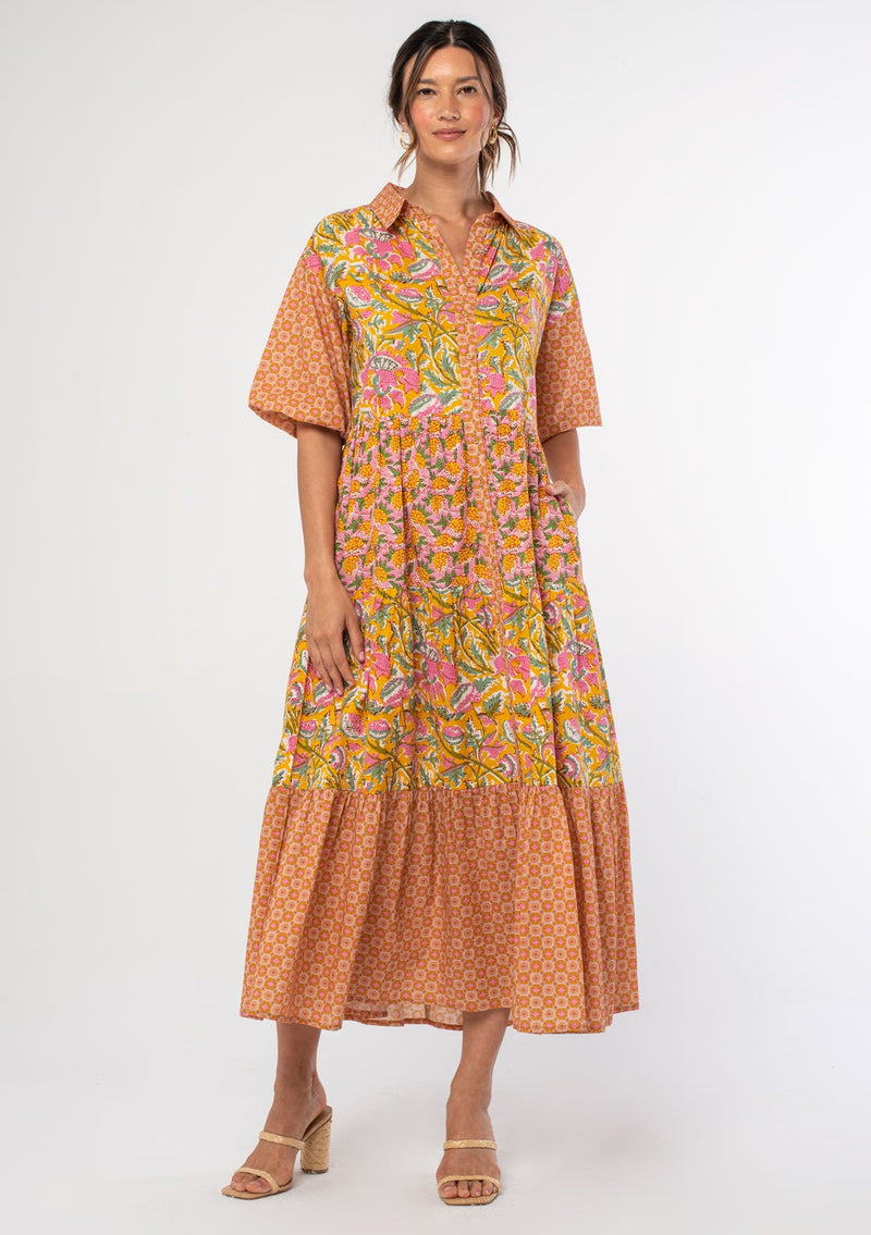 [Color: Pink/Mango] A woman wearing a flowy cotton bohemian maxi dress in a bright pink and yellow mixed floral print. With half length puff sleeves, a collared neckline and a button front. 