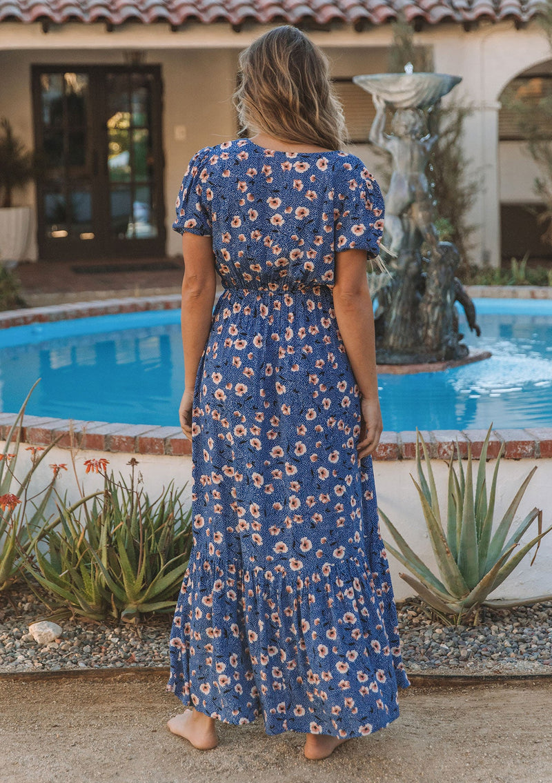 [Color: Navy/Cream] A model wearing a vintage inspired maxi dress in a navy blue floral print. With short puff sleeves, a surplice v neckline, and a side slit.
