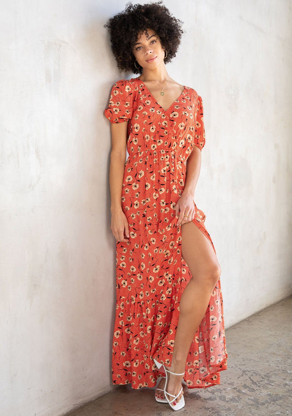 [Color: Red/Natural] A model wearing a vintage inspired maxi dress in a red floral print. With short puff sleeves, a surplice v neckline, and a side slit. 