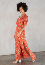 [Color: Red/Natural] A model wearing a vintage inspired maxi dress in a red floral print. With short puff sleeves, a surplice v neckline, and a side slit. 
