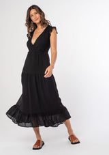 [Color: Black] A model wearing a black mid length dress with a lace up strappy back and short flutter sleeves.