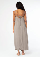 [Color: Cement] A back facing image of a black model wearing a flowy grey bohemian summer maxi dress with strappy back and wooden bead details.