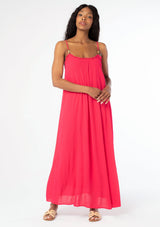 [Color: Hot Pink] A front facing image of a black model wearing a flowy bright pink bohemian summer maxi dress with strappy back and wooden bead details.