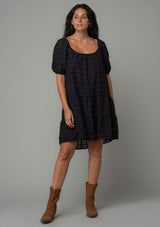 [Color: Black] A model wearing a bohemian black cotton mini dress with short puff sleeves and a relaxed flowy fit.