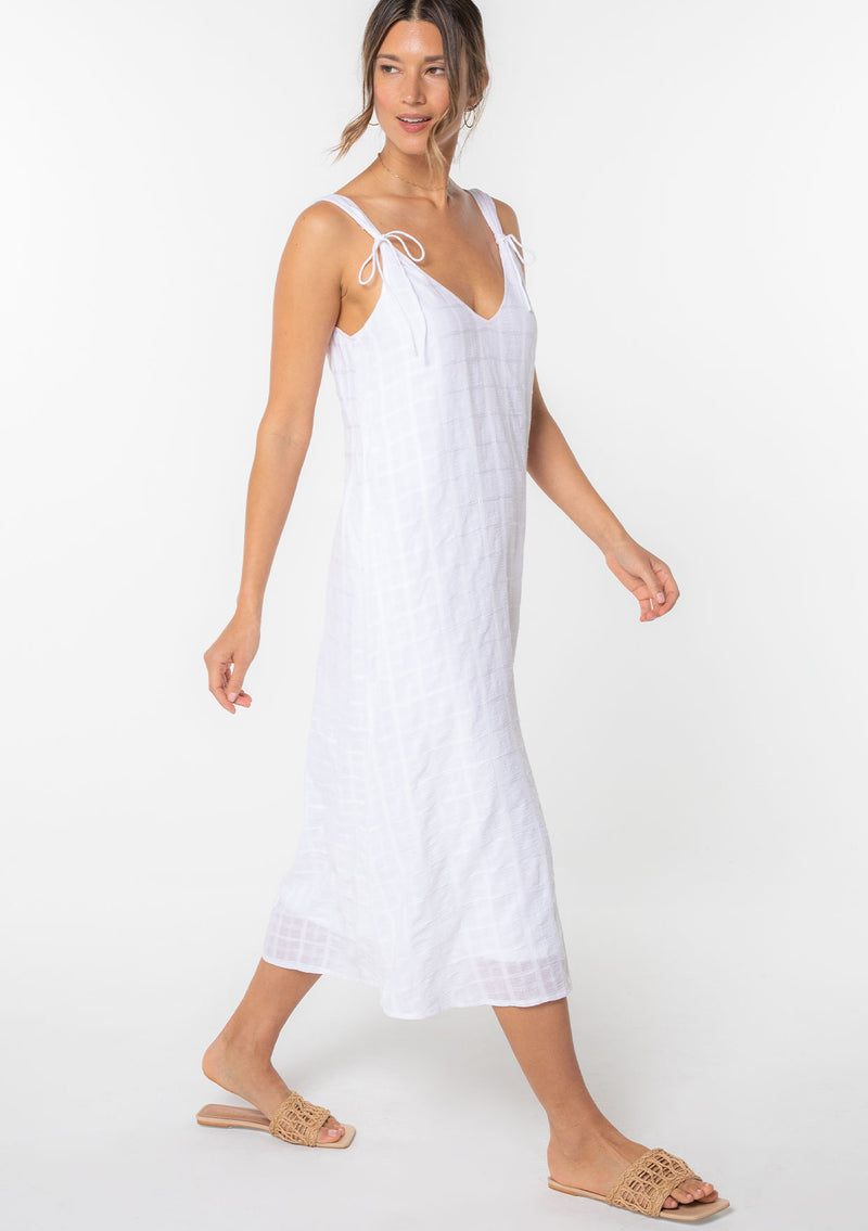 [Color: White] A model wearing a bohemian cotton white mid length dress with tank top straps and a v neckline in front and back. 