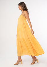 [Color: Sherbert] A woman wearing a yellow flowy bohemian maxi dress with crochet trim, gold toned hardware, and adjustable spaghetti straps.