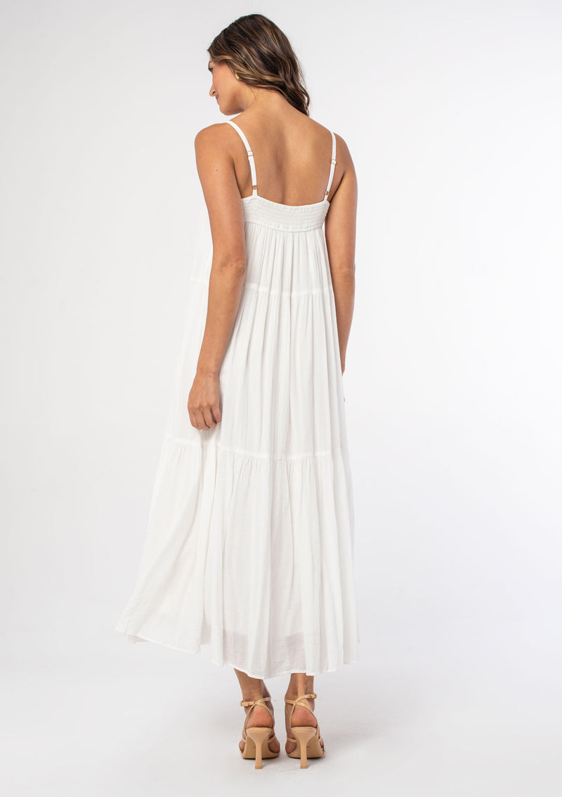 [Color: White] A woman wearing a white flowy bohemian maxi dress with crochet trim, gold toned hardware, and adjustable spaghetti straps.