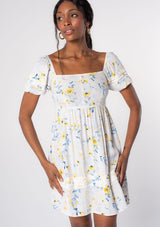 [Color: Cream/Yellow] A model wearing a white, yellow, and blue floral print puff sleeve mini dress. 