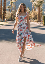 [Color: Ivory/Red] A model wearing a white bohemian maxi dress with pink and red tropical floral print. With a slim fit smocked bodice and a flowy skirt. 