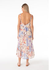 [Color: Natural/Rust] A back facing image of a blonde model wearing an ultra flowy cotton bohemian spring maxi dress in a pink and blue floral print. With elastic tank top straps, a scooped neckline, a low back, a tiered silhouette, and side pockets. 