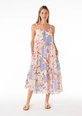 [Color: Natural/Rust] A front facing image of a blonde model wearing an ultra flowy cotton bohemian spring maxi dress in a pink and blue floral print. With elastic tank top straps, a scooped neckline, a low back, a tiered silhouette, and side pockets. 