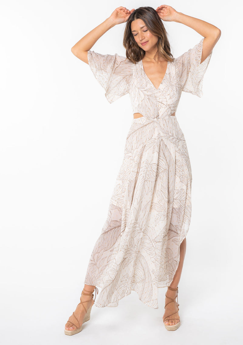 [Color: Natural/Taupe] A model wearing a natural colored leaf print maxi dress in sheer chiffon. With metallic gold clip dot details, side waist cutouts, and short flutter sleeves. 