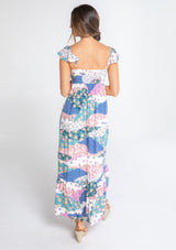 [Color: Ivory/Jade] A model wearing a white, pink, and blue floral patchwork print maxi dress with a sweetheart neckline, short flutter sleeves, and an empire waist. 