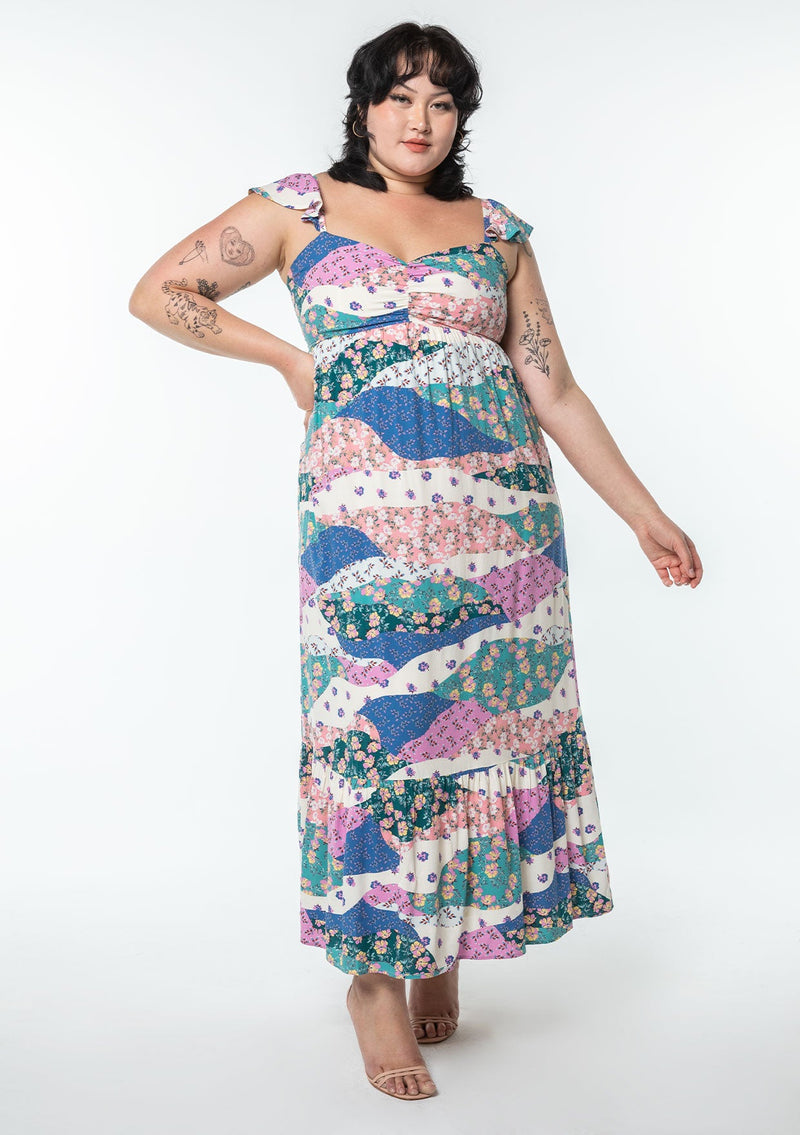 [Color: Ivory/Jade] A model wearing a white, pink, and blue floral patchwork print maxi dress with a sweetheart neckline, short flutter sleeves, and an empire waist.