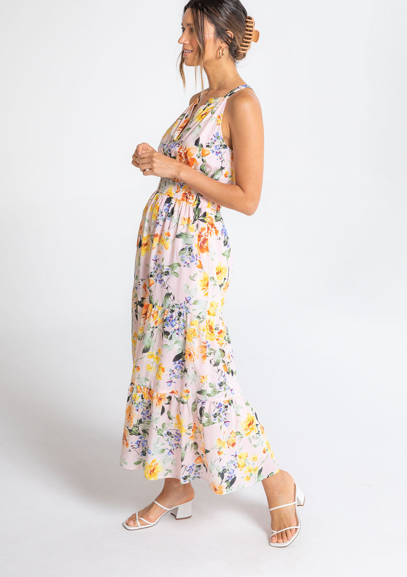 [Color: Blush/Orange] A model wearing a romantic bohemian halter maxi dress in a pink and orange large floral print. 