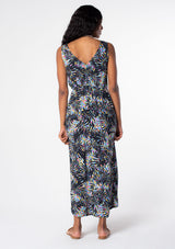 [Color: Black/Blue] A model wearing a black sleeveless resort maxi dress with multi color palm print and a twist front waist detail. 