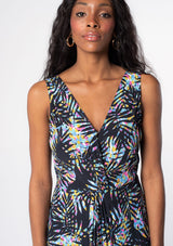[Color: Black/Blue] A model wearing a black sleeveless resort maxi dress with multi color palm print and a twist front waist detail. 
