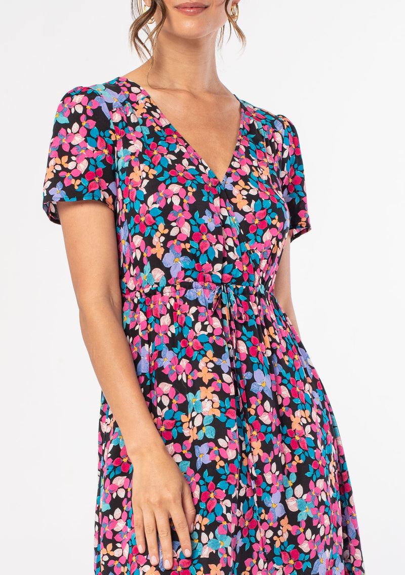 [Color: Black/Fuchsia] A woman wearing a casual bohemian mid length short sleeve summer dress in a black and pink floral print. 