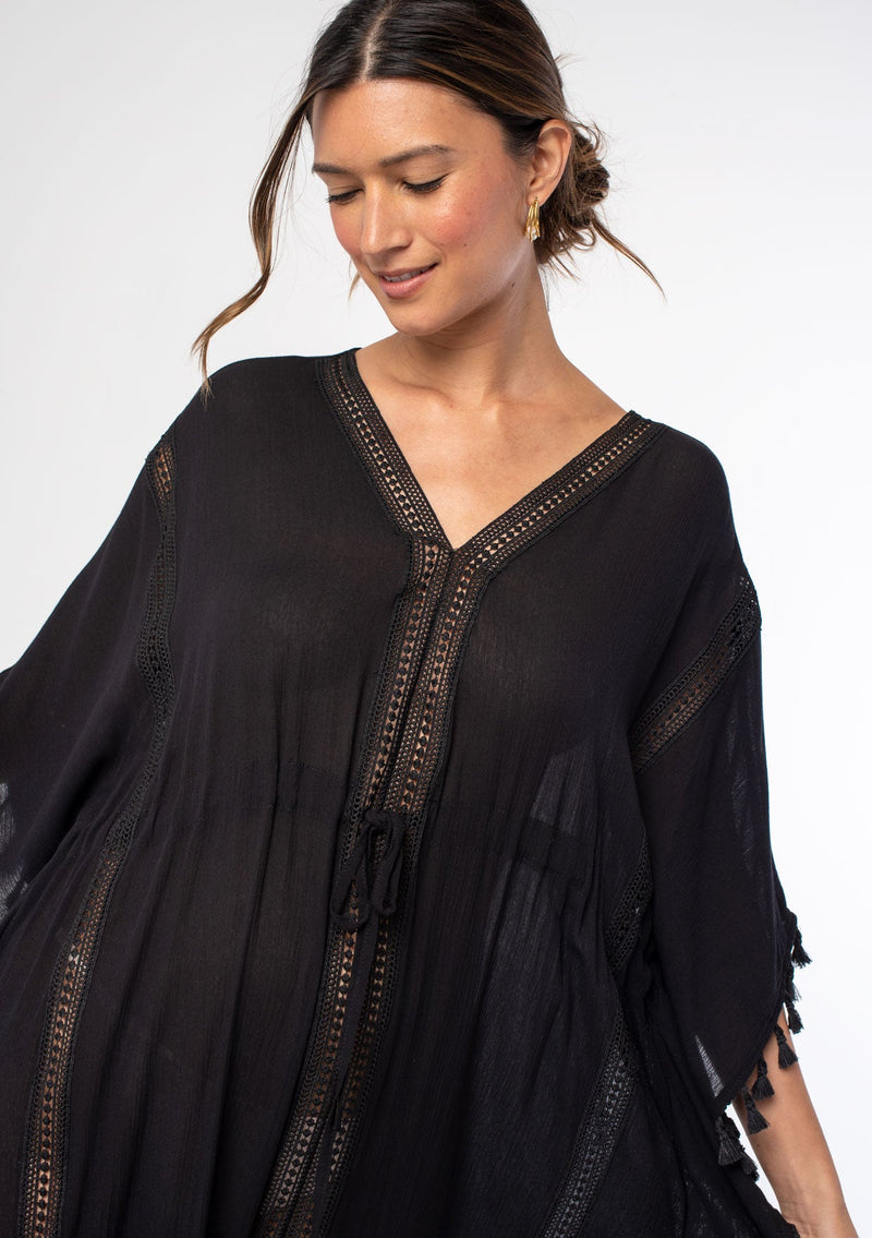 [Color: Black] A woman wearing a sheer black bohemian beach cover up maxi dress with lace and tassel trim and side slits. A kimono kaftan maxi dress perfect for vacations! 